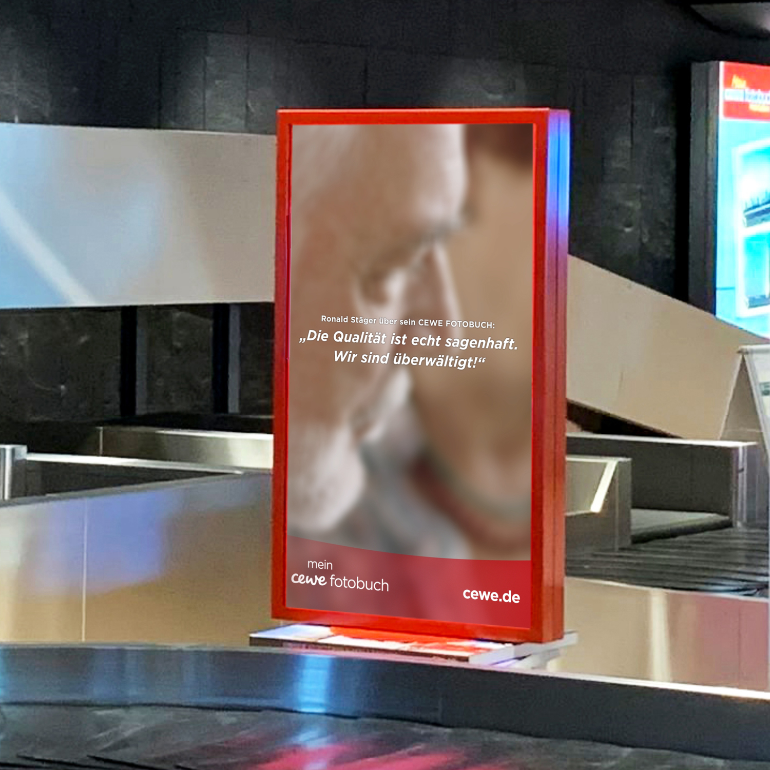 Werbeplakate mit CEWE-Fotobuch-Werbung an einem Gepäckband.