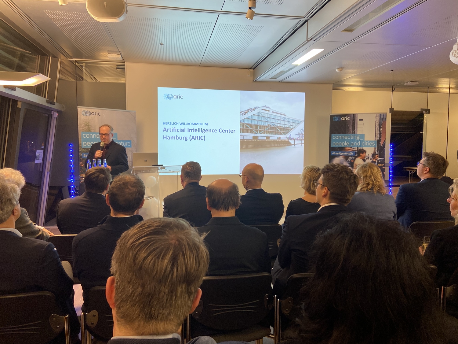 Präsentation vor Publikum mit einer Projektion auf der Leinwand.