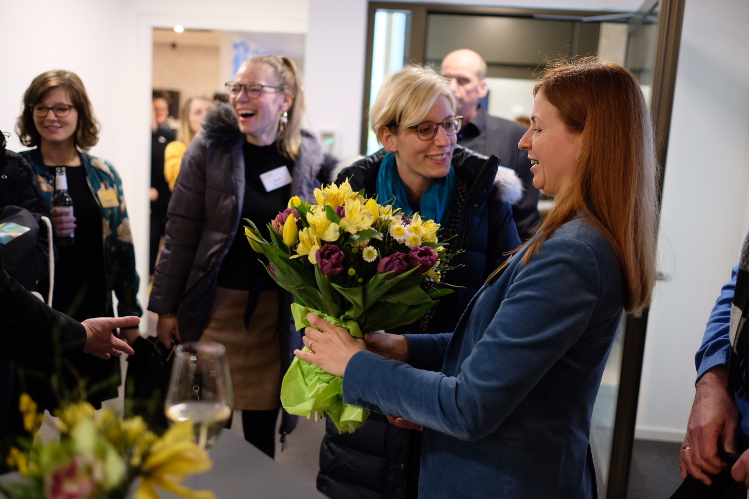 Frau erhält einen Blumenstrauß, während sie mit anderen Teilnehmern lacht.