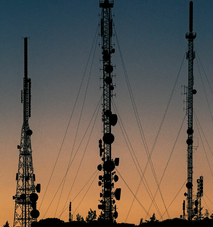 Mehrere Mobilfunkmasten vor einem bewölkten Himmel.