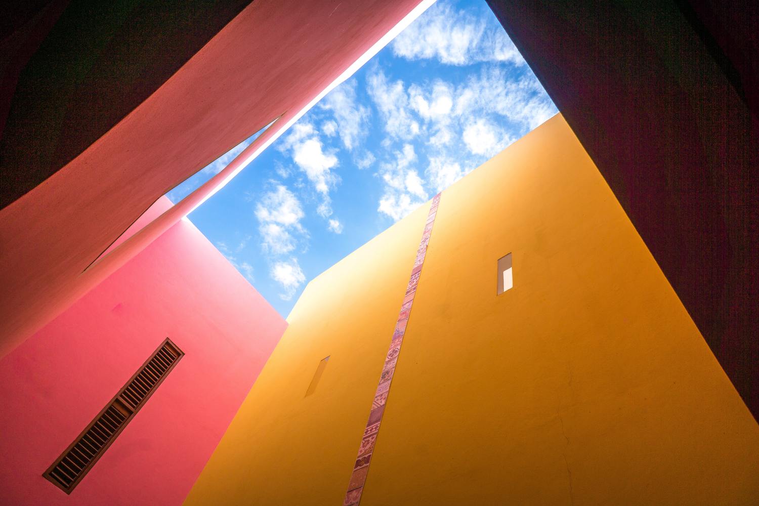 Gebäude mit gelben und roten Wänden und einem blauen Himmelsausschnitt.