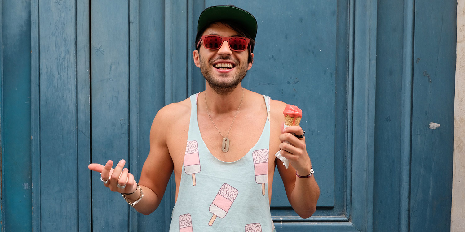 Ein Mann mit Sonnenbrille hält ein Eis und lächelt.