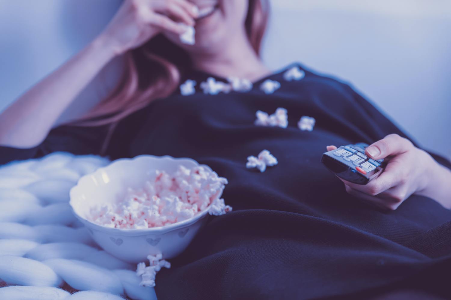 Person isst Popcorn und schaut fern.