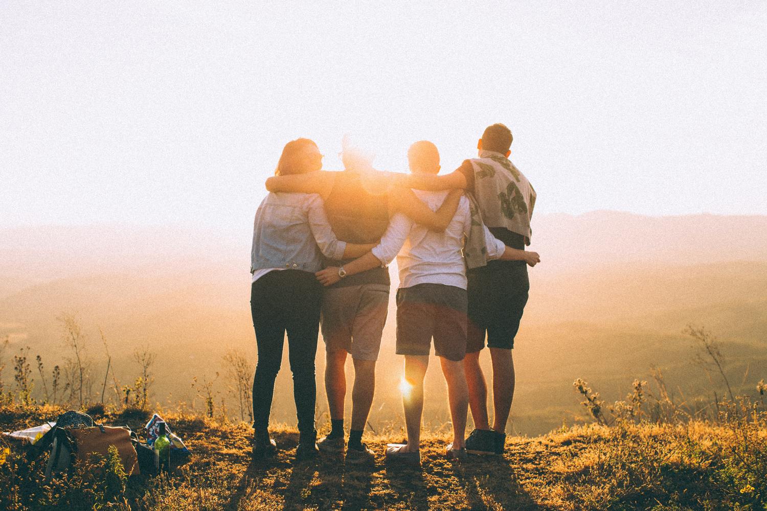 Gruppe von Freunden umarmt sich im Sonnenuntergang.