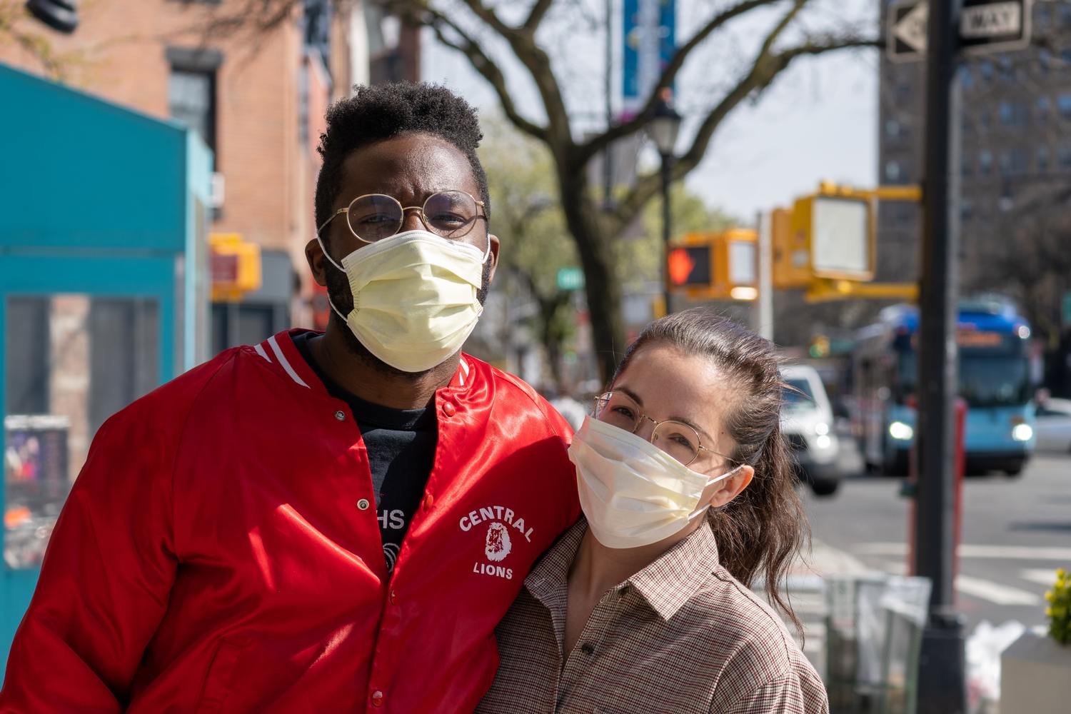 Zwei Personen mit Gesichtsmasken stehen zusammen auf einer Straße.