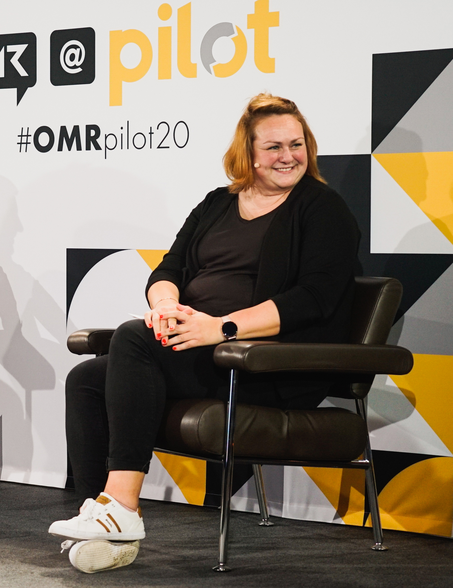 Frau sitzt lächelnd auf der Bühne bei OMR-pilot20.