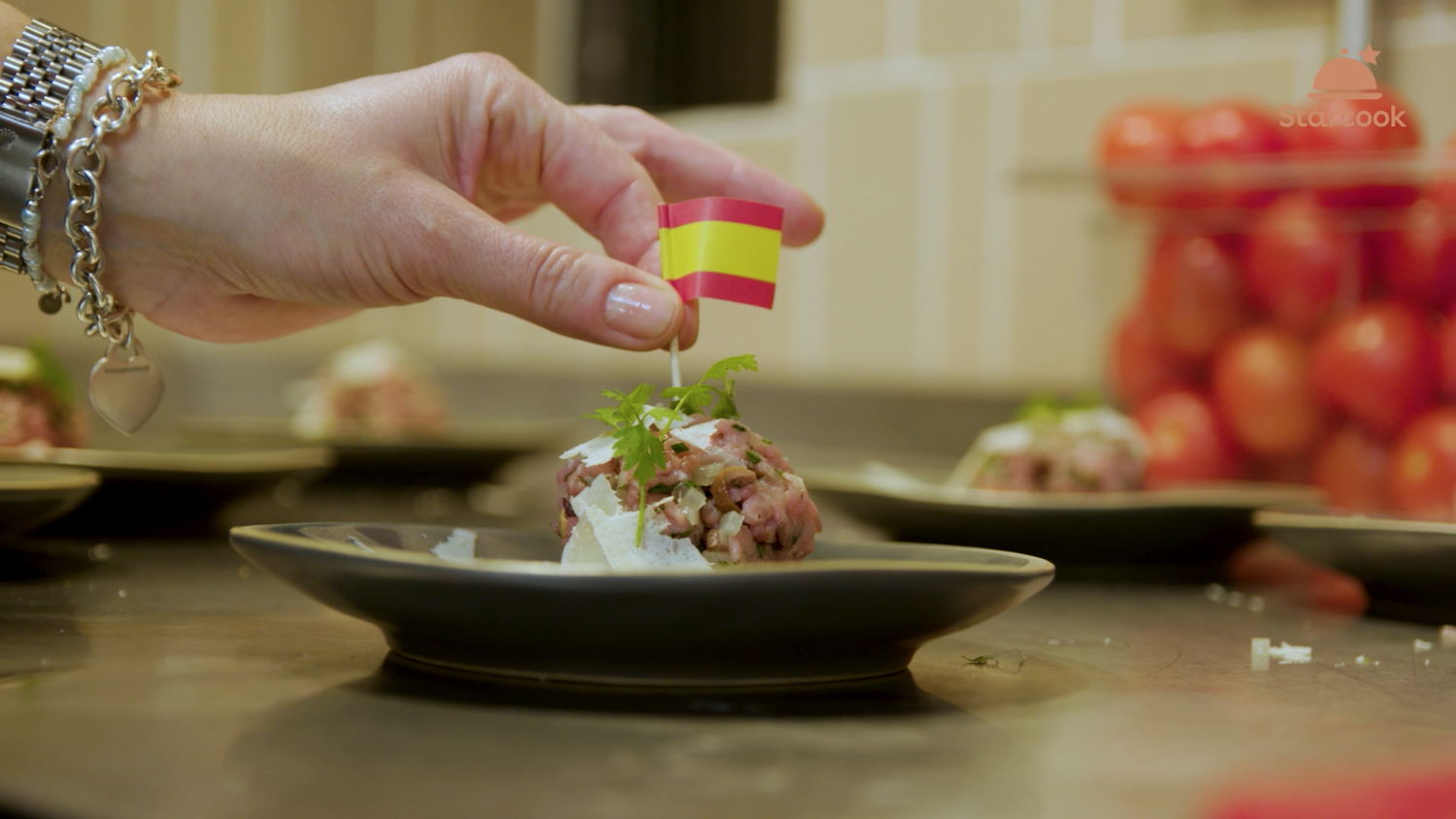 Eine Hand verziert ein Gourmetgericht mit einer Mini-Flagge.