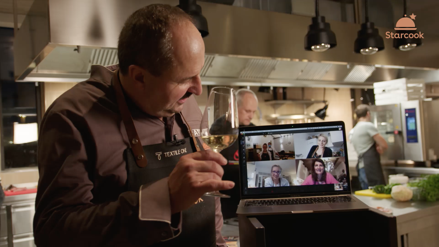 Ein Koch mit einem Glas Sekt während einer Online-Konferenz.
