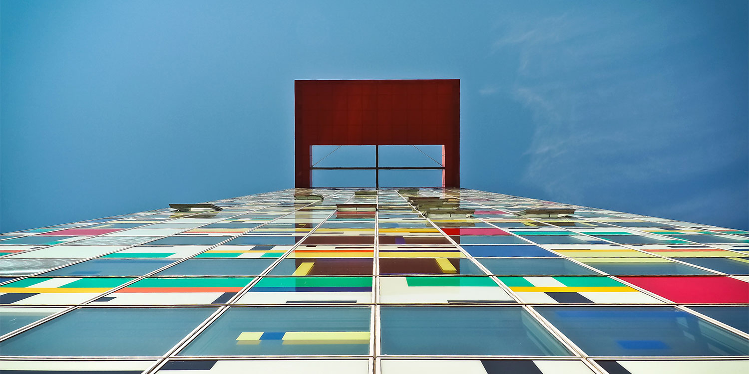 Ein modernes Gebäude mit einer farbigen Glasfassade und einem roten architektonischen Element oben.
