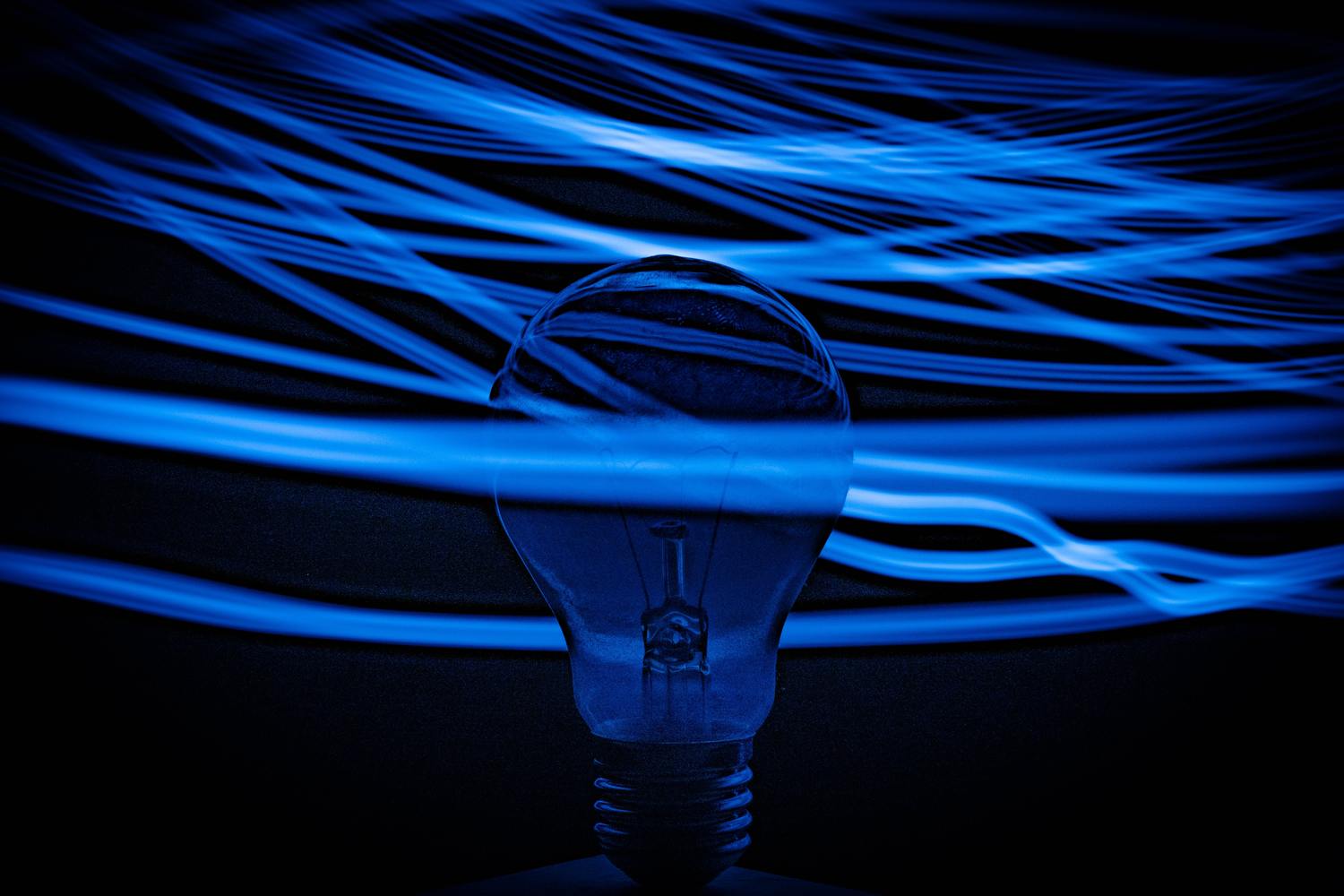 Eine Glühbirne mit blauen Lichtspuren im Hintergrund, die den Eindruck von Innovation vermittelt.