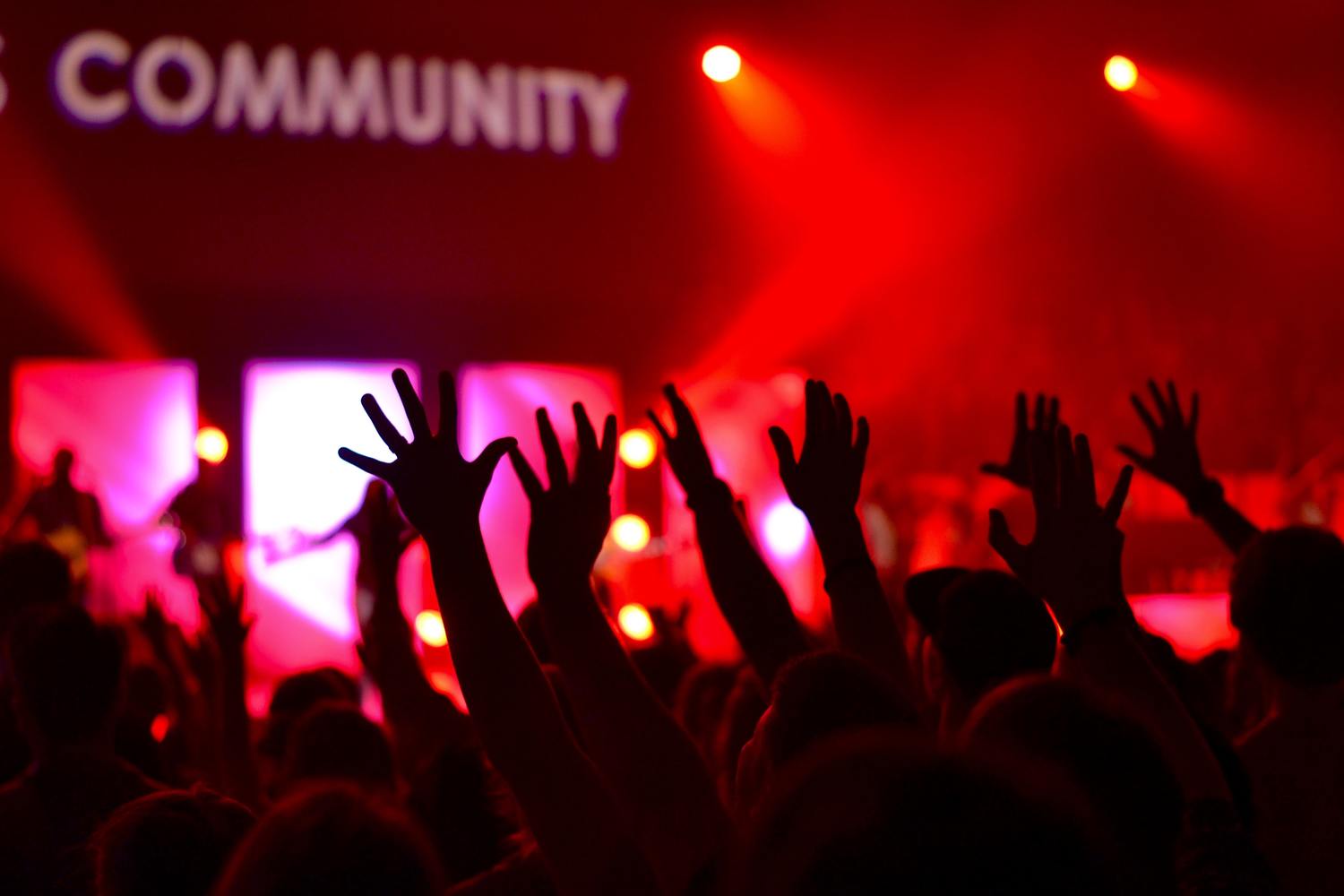 Menschen feiern bei einem Konzert mit erhobenen Händen.
