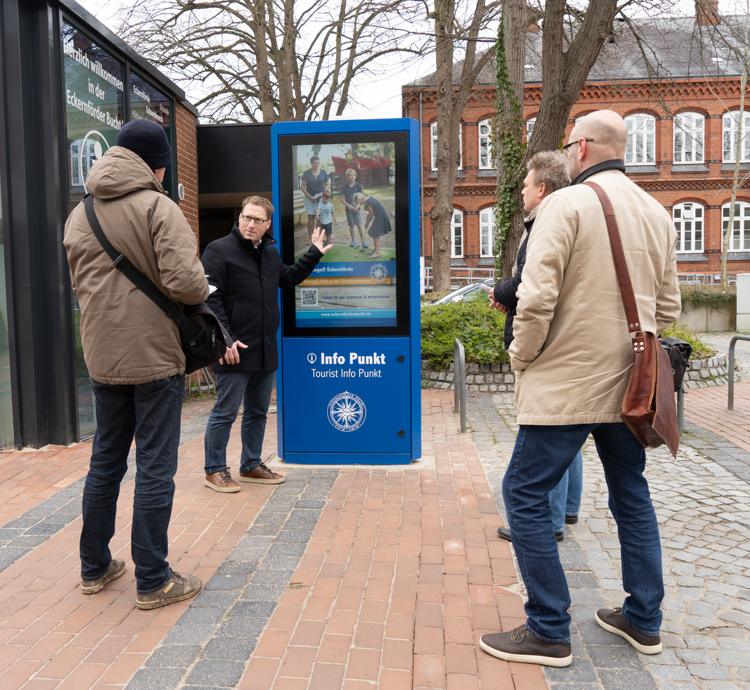 Mensch interagiert mit einem digitalen Informationspunkt im Freien.