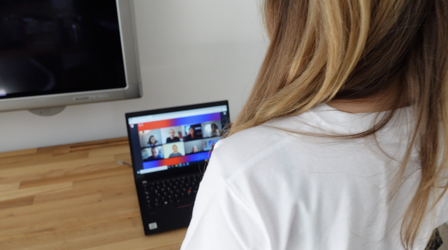 Person sitzt vor einem Laptop bei einer Videokonferenz.