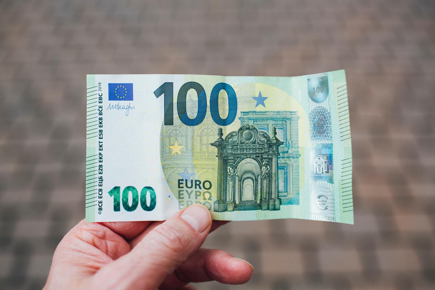 Person hält einen 100-Euro-Schein.