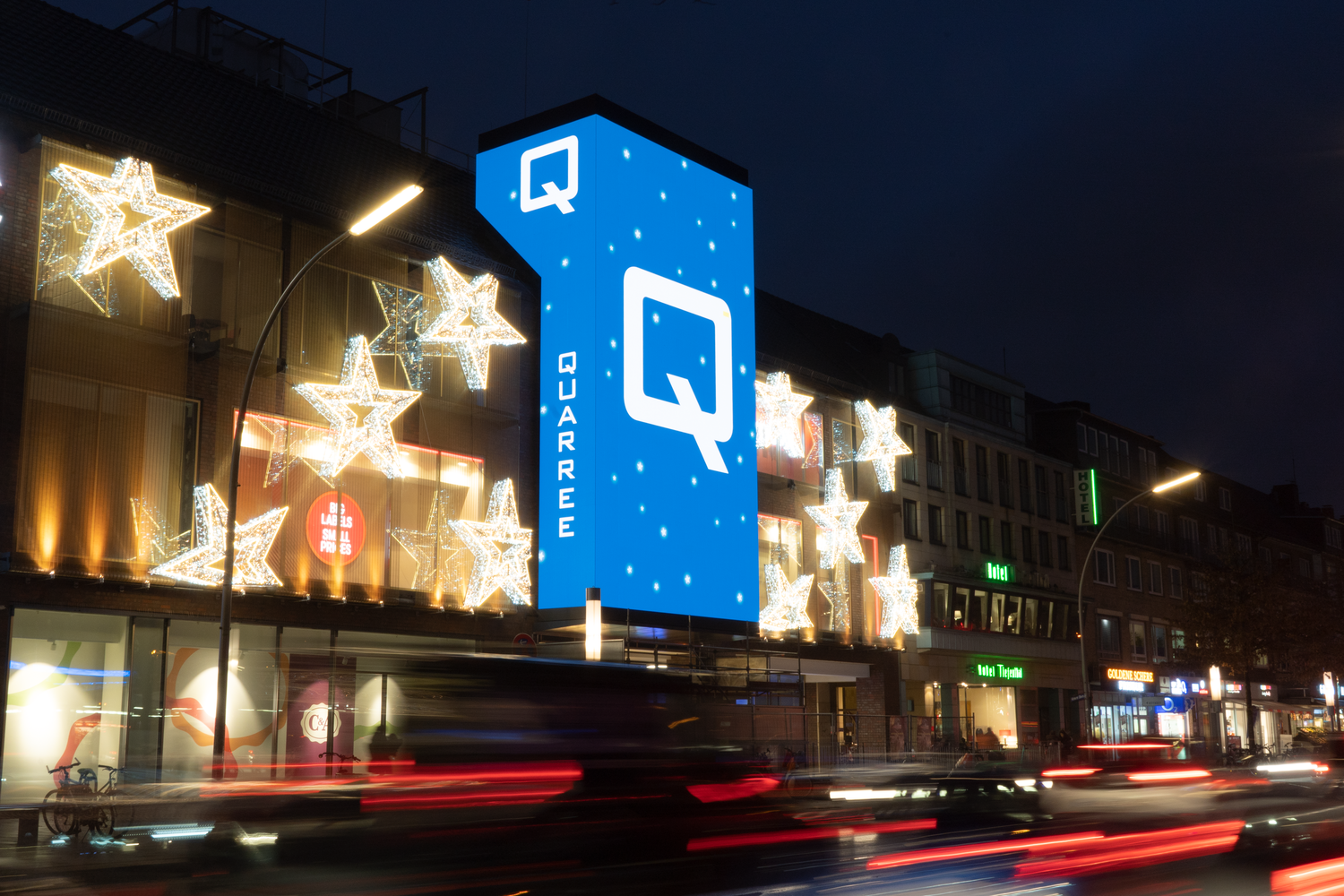 Leuchtende Werbetafel mit blauem Design in einer Stadt bei Nacht.