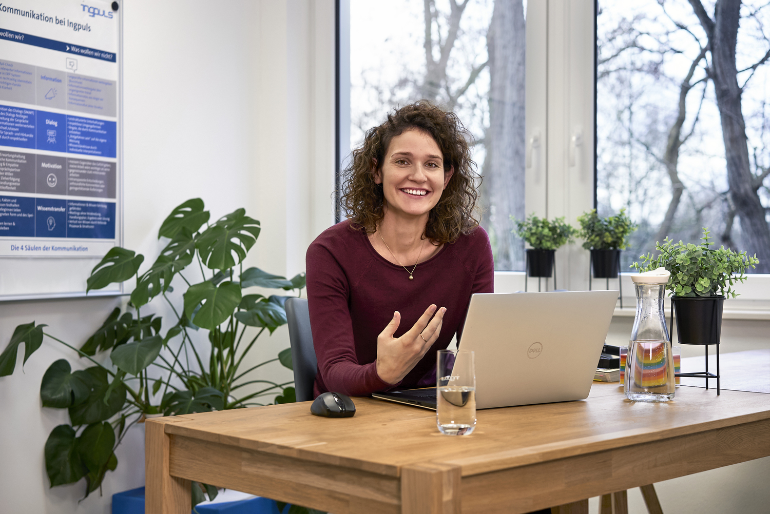Frau sitzt an einem Schreibtisch mit Laptop und spricht