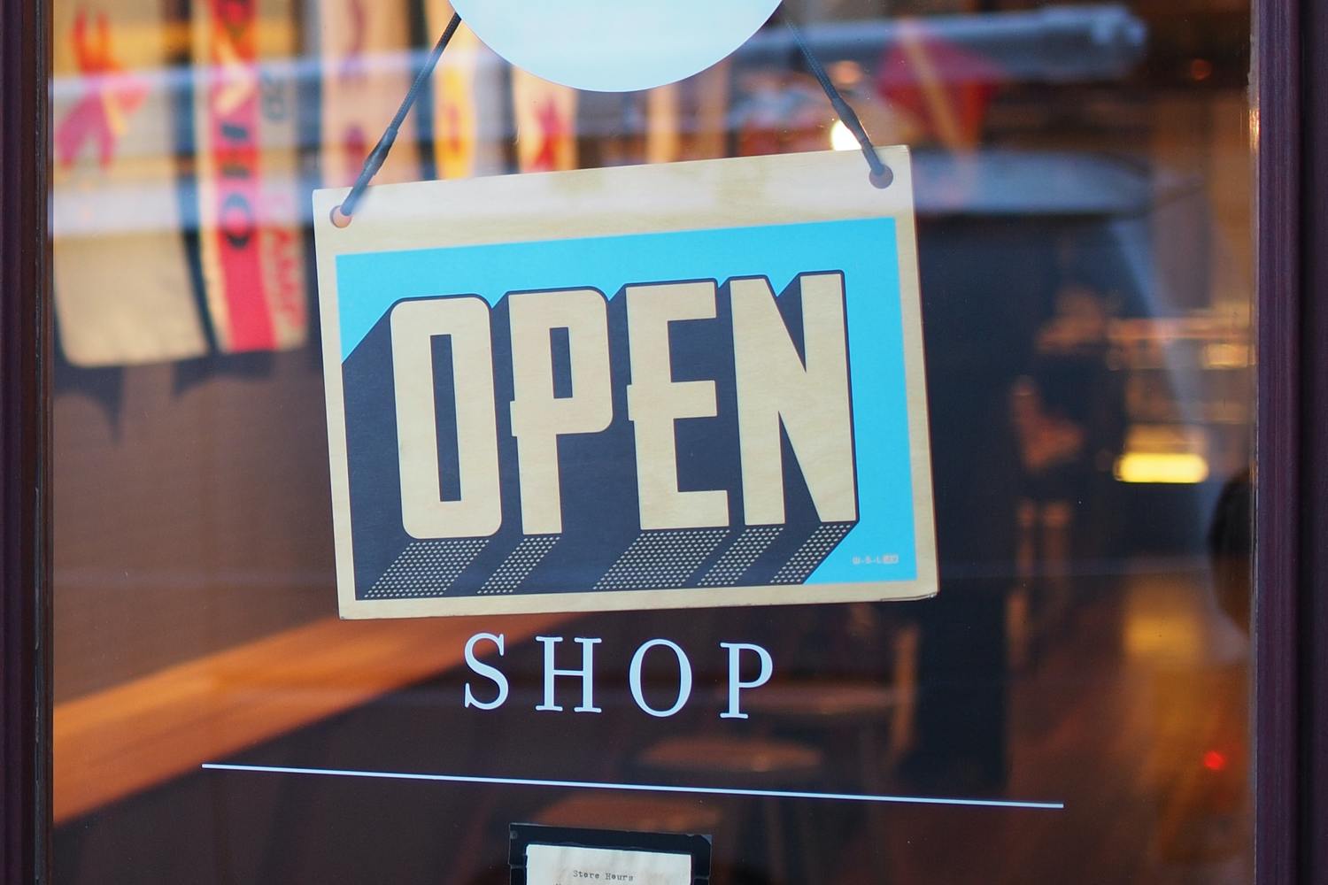 Schild mit der Aufschrift „OPEN“ an einer Glastür.