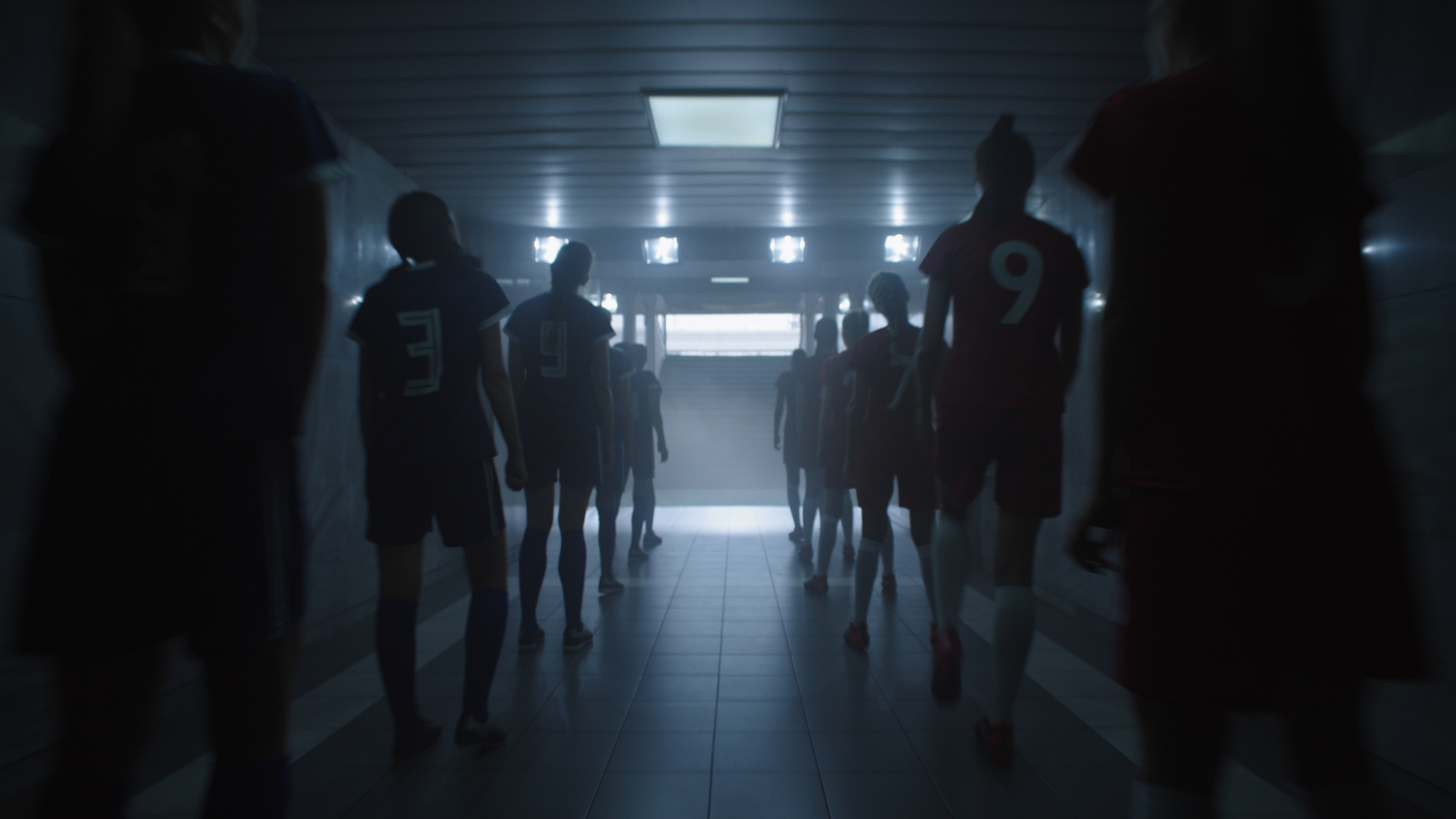 Gruppe von Fußballspielern geht durch einen dunklen Gang.