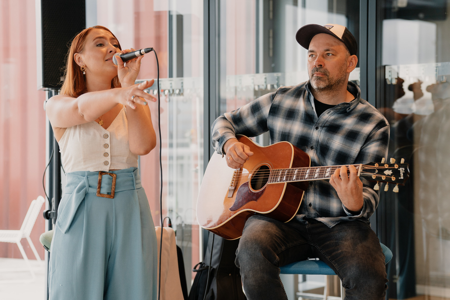 Musikerin singt, begleitet von einem Gitarristen.