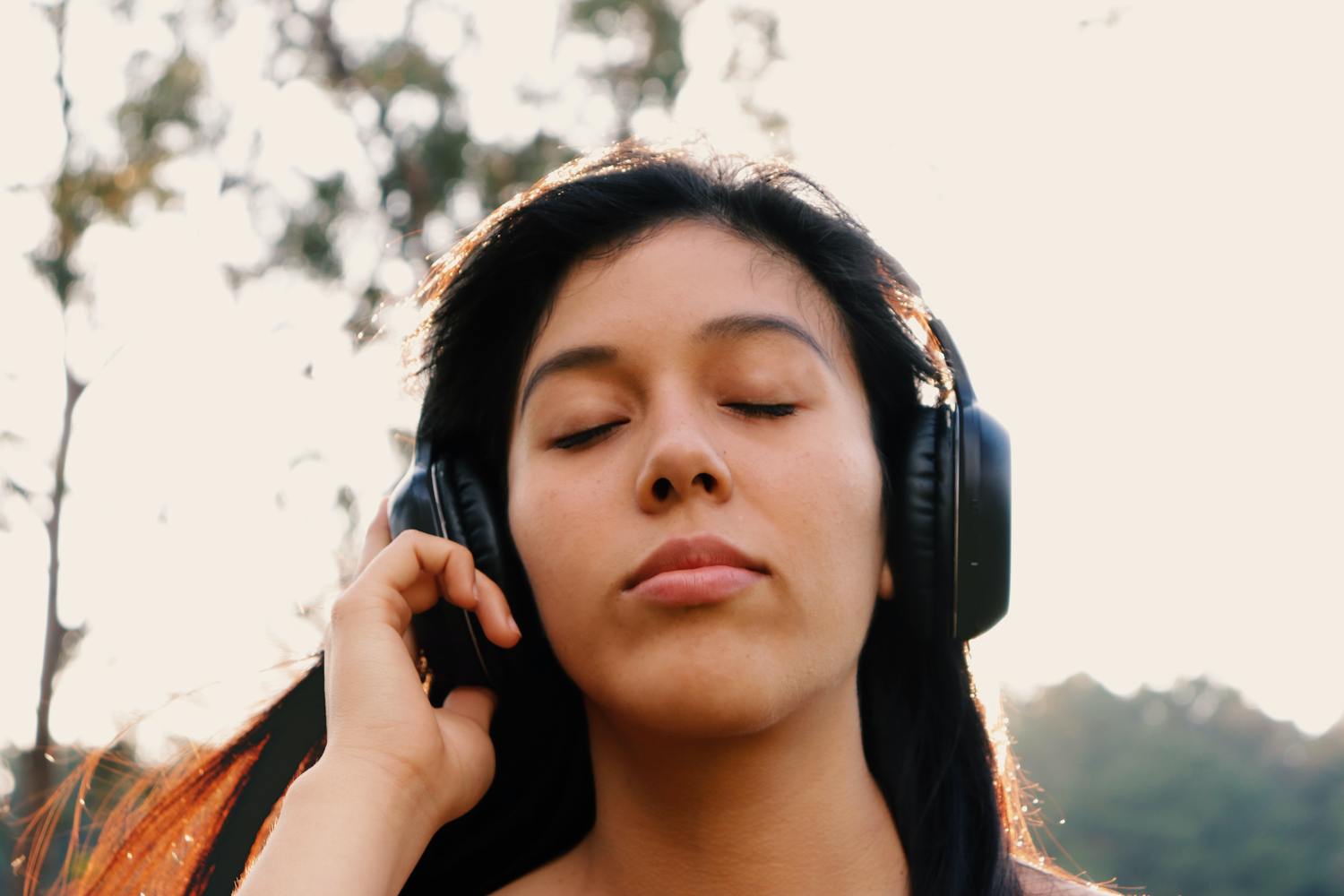 Frau hört mit geschlossenen Augen Musik über Kopfhörer.