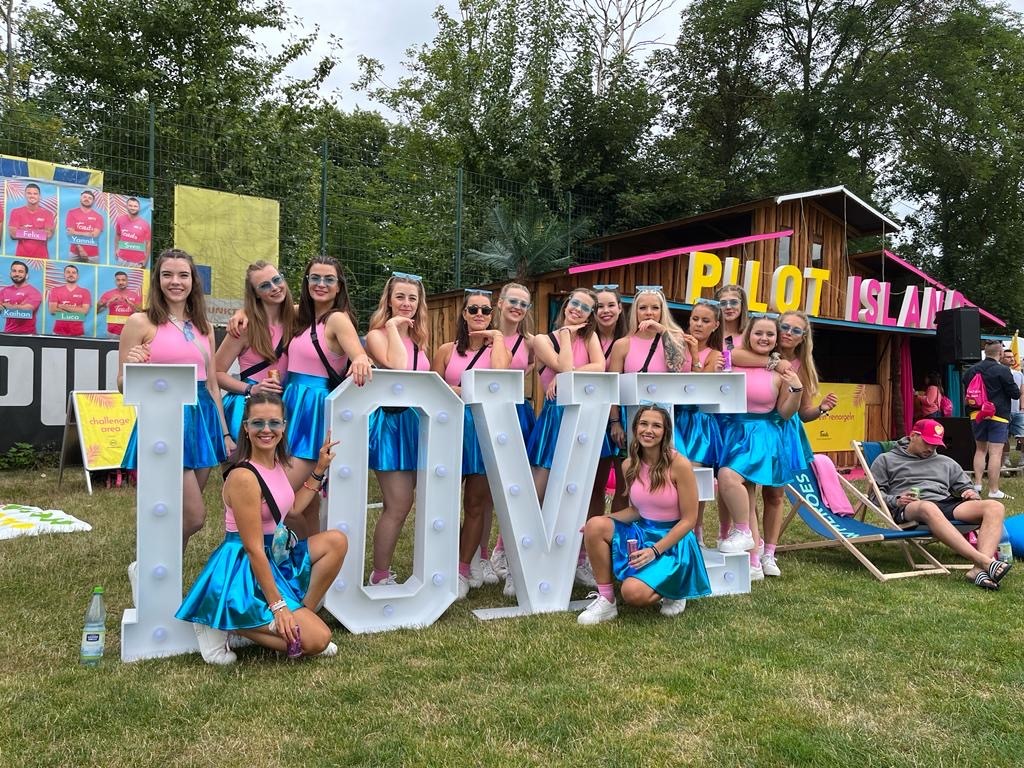Gruppe posiert vor einem „LOVE“-Schild im Freien.