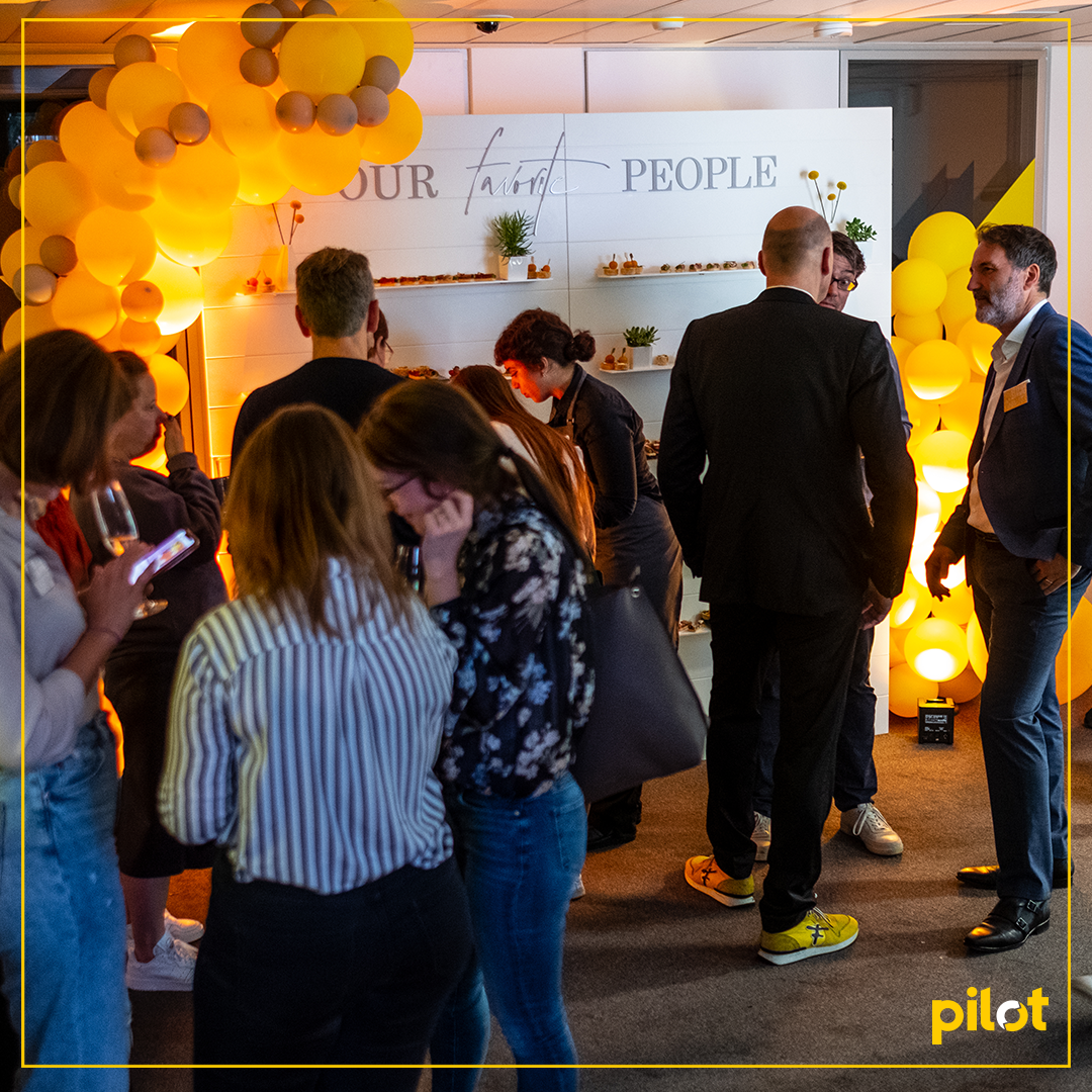 Menschen auf einer Abendveranstaltung mit „pilot“-Branding.