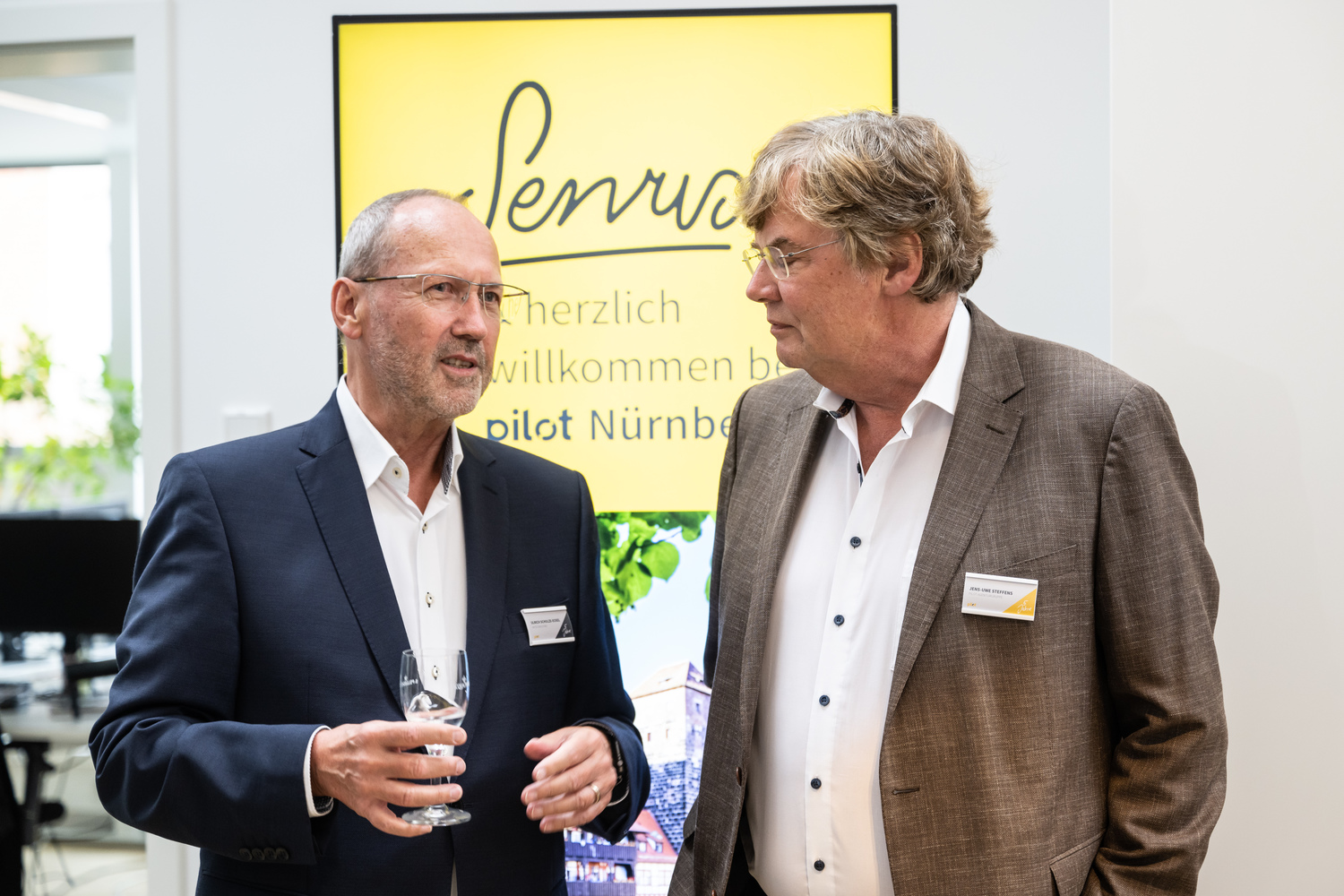 Zwei Männer mit Getränken unterhalten sich.