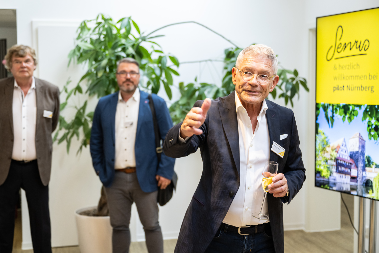 Mann im Anzug mit Weinglas in der Hand.