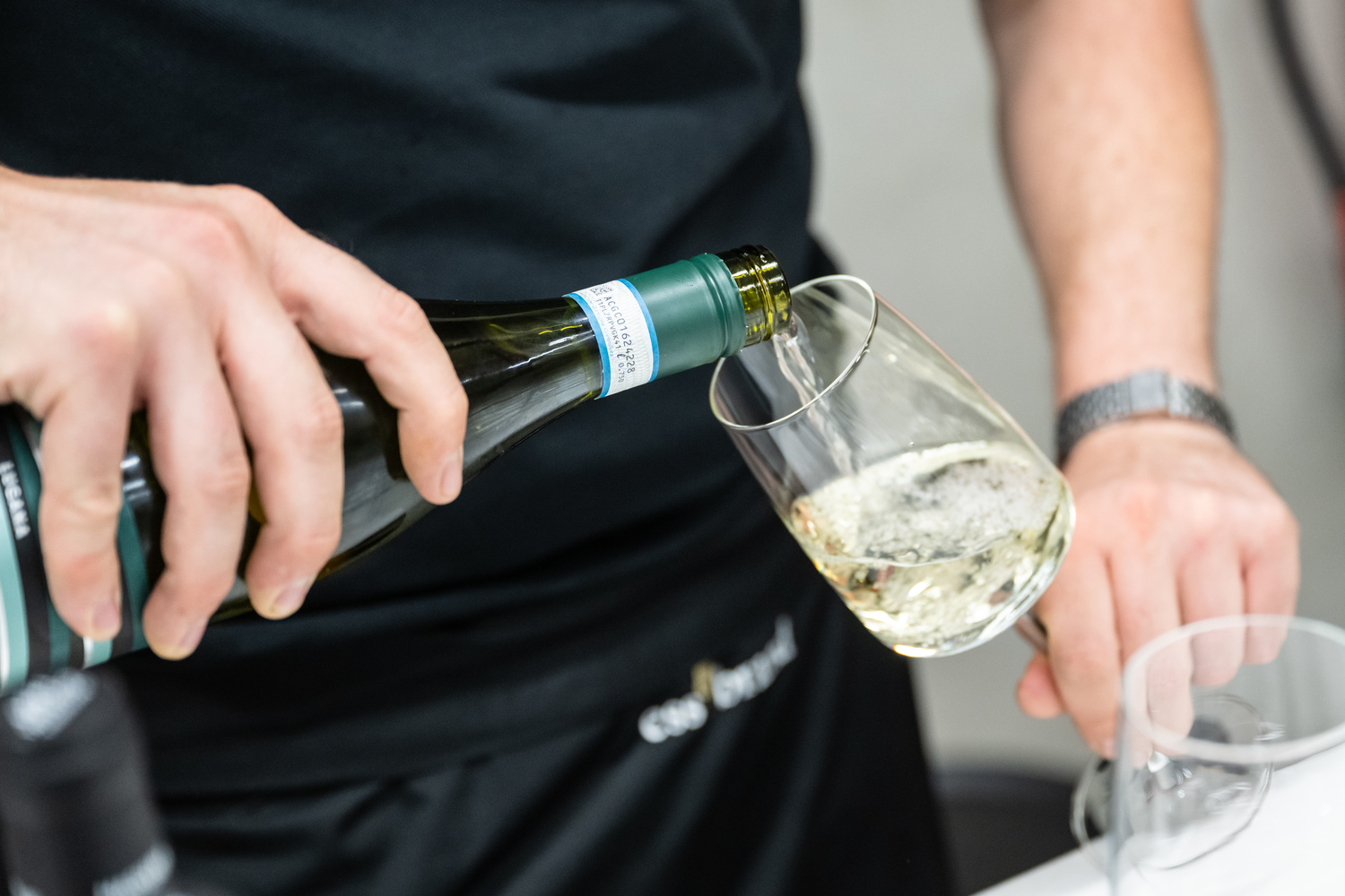 Person gießt Weißwein in ein Glas.