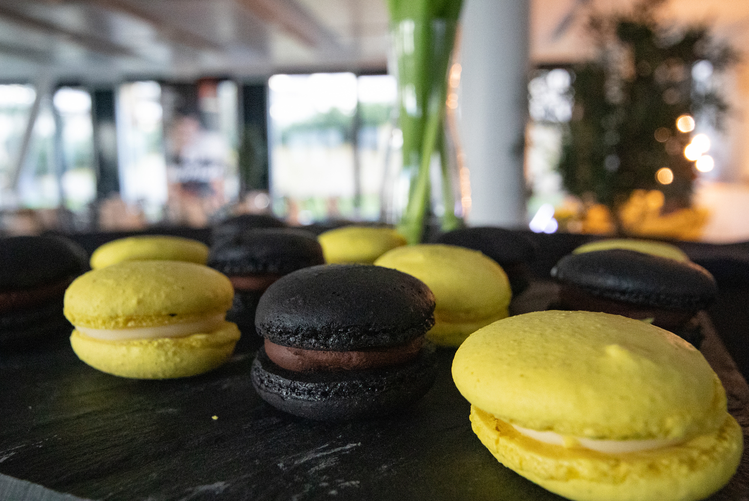 Schwarze und gelbe Macarons auf einem Teller.