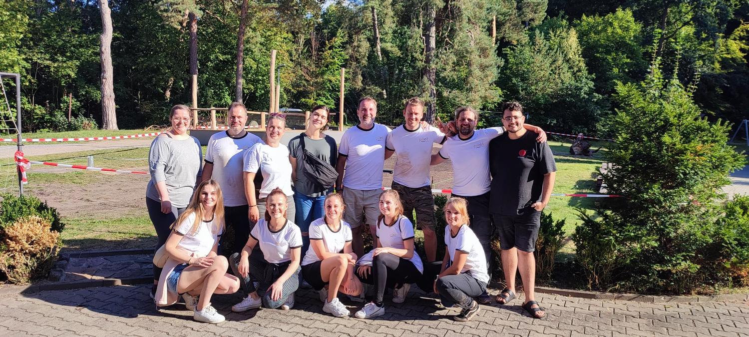 7 Menschen stehen zusammen und lächeln für ein Foto beim Umgestalten eines Gartens.