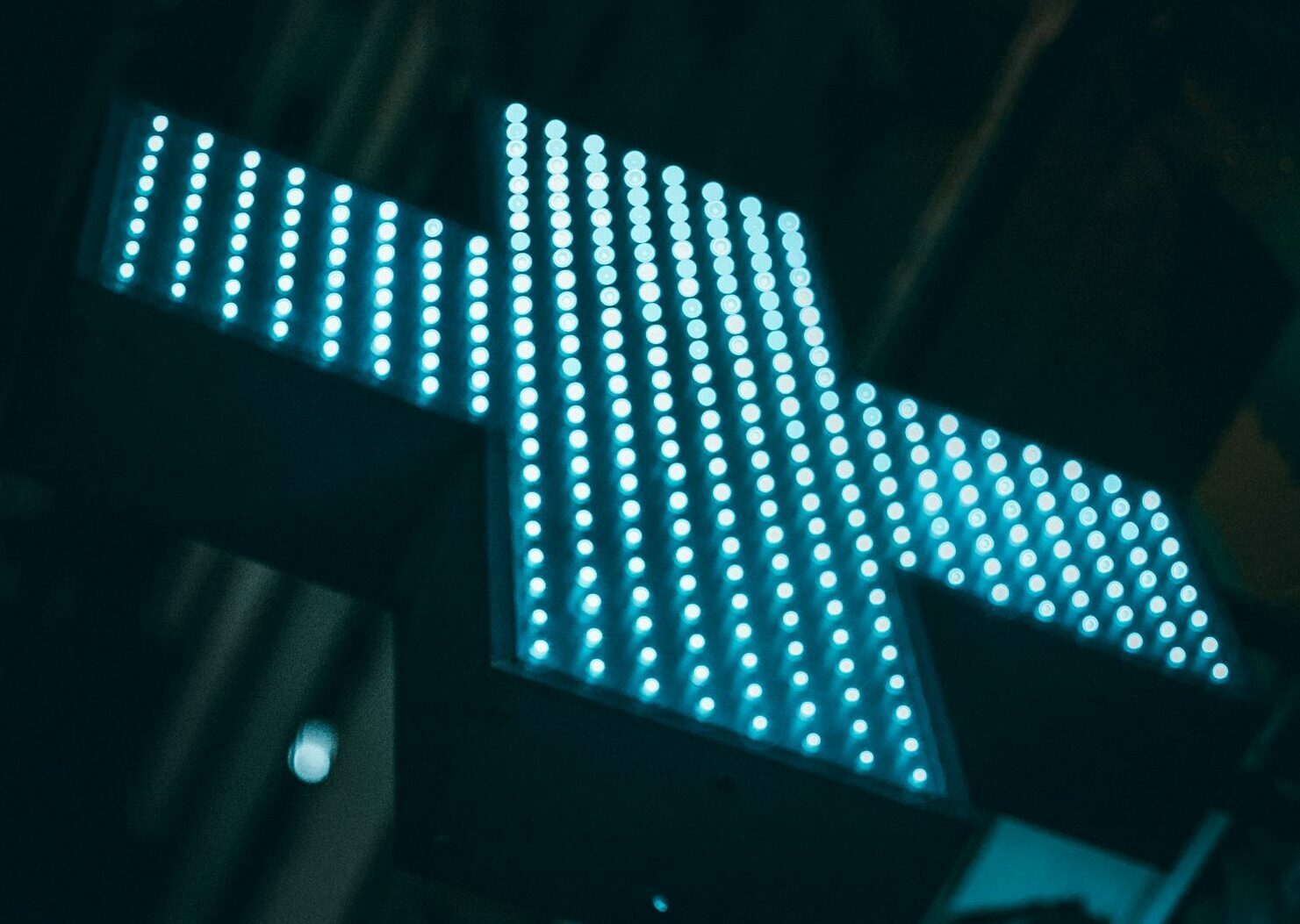 Ein leuchtendes blaues LED-Kreuz in der Nacht.