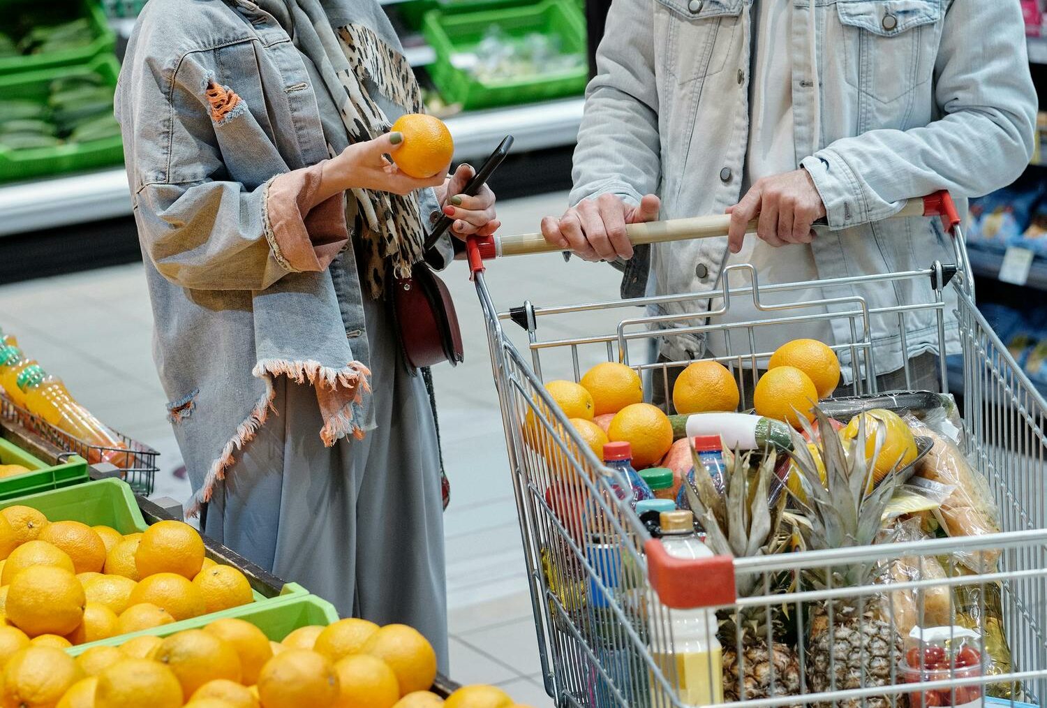 Mann und Frau stehen in einem Supermarkt und wählen gemeinsam Lebensmittel aus.