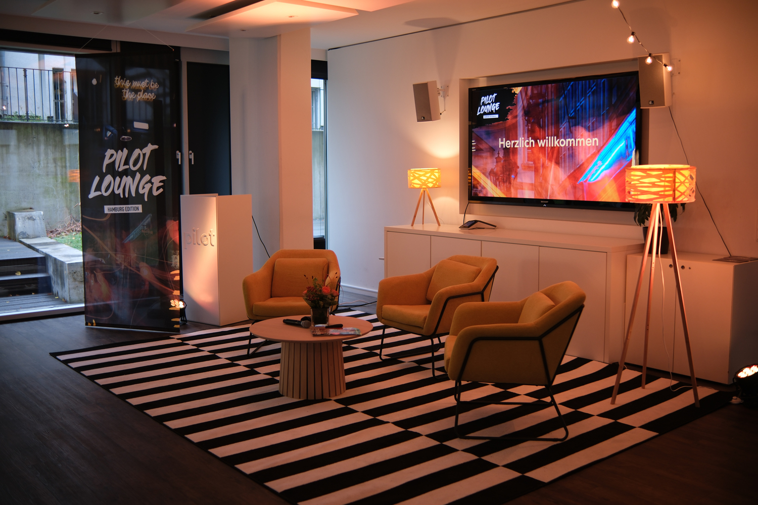 Pilot Lounge Set-Up mit Sesseln, TV und Bannern.
