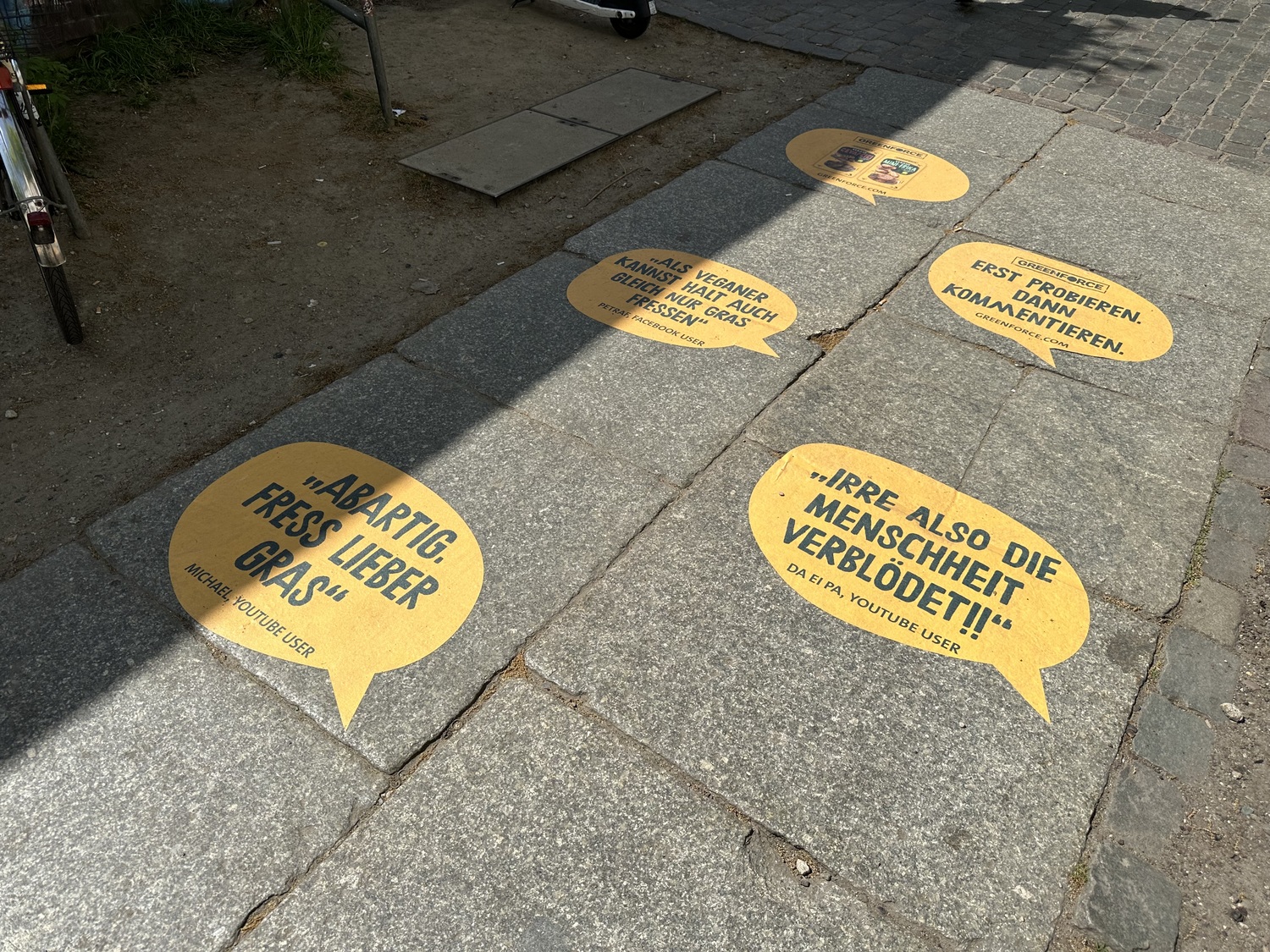 Weitere Greenforce-Werbesprüche auf dem Gehweg, die verschiedene Zitate darstellen.