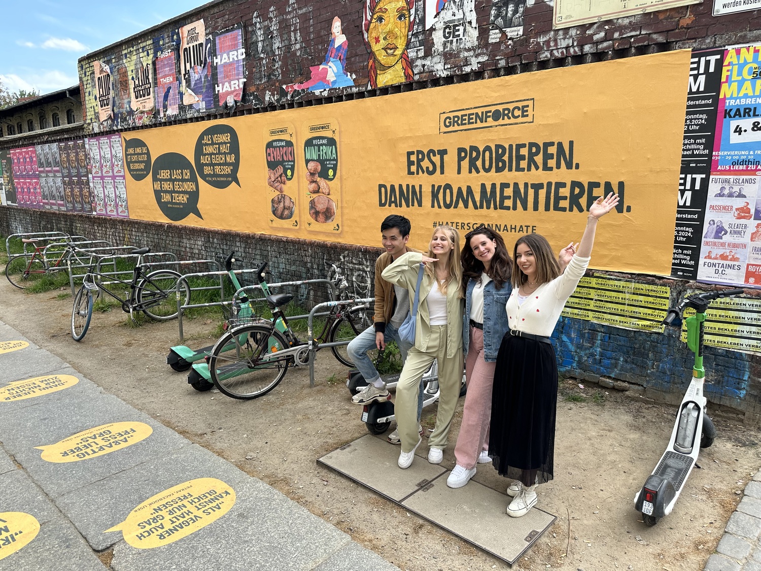 Eine Gruppe von Menschen posiert vor einer Greenforce-Werbewand mit dem Slogan 