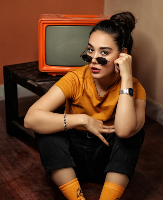 Alireza Esmaeeli RoCrQdjxbeo Unsplash Frau sitzt mit leicht heruntergezogenen Sonnenbrille vor Fernseher