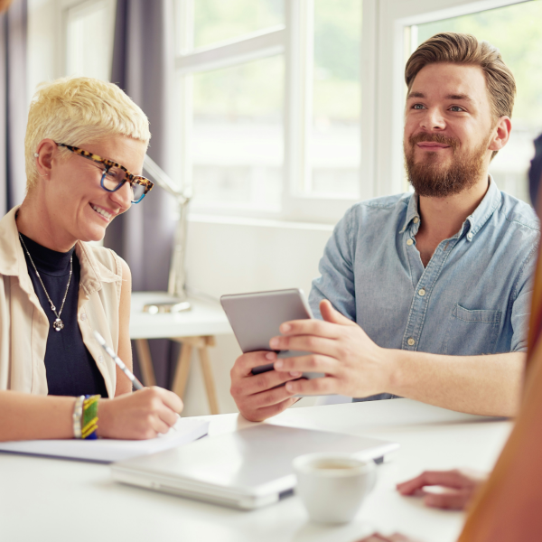 Zwei junge Menschen sitzen am Tisch und arbeiten zusammen