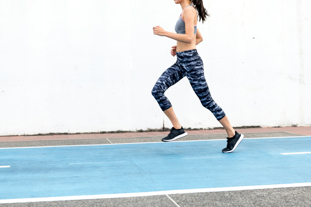 Joggerin in Leggings und Top auf einer blauen Tartan Bahn