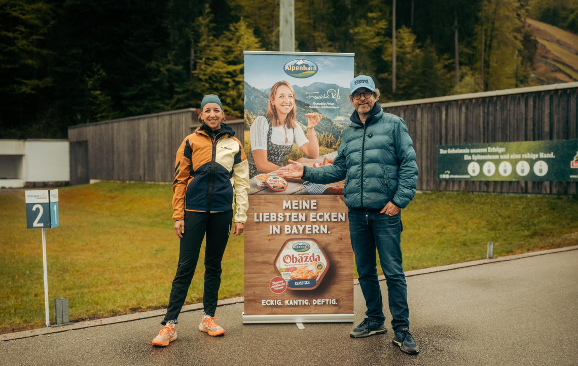 Biathletin Franziska Preuß und Jürgen Irlbacher vor einem Obazda Aufsteller