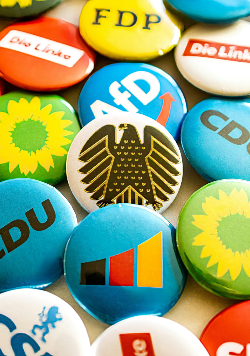 Buttons mit unterschiedlichen Partei Logos darauf, in der MItte einer mit deutschem Adler