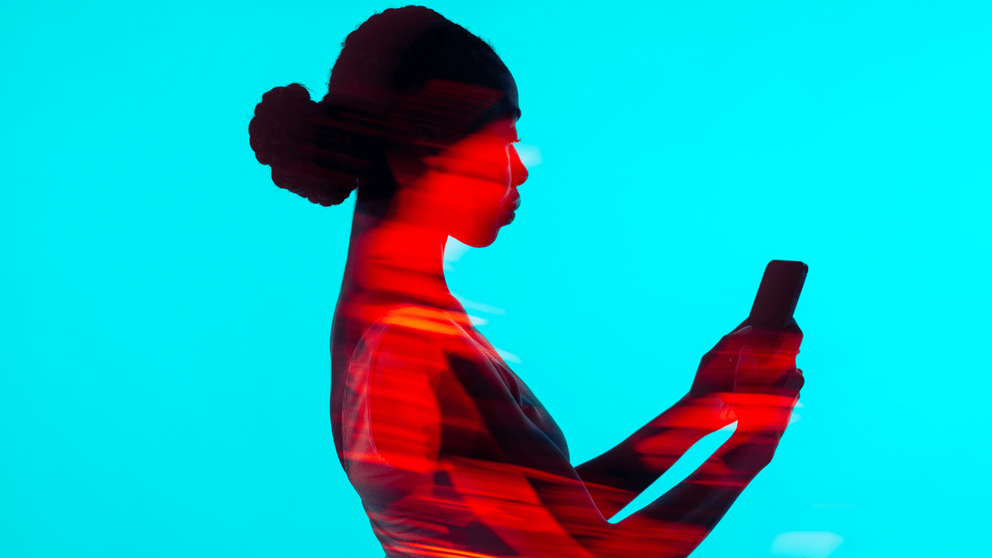 Eine Frau ist seitlich im Profil zu sehen, wie sie ihr Handy in der Hand hält und auf den Bildschirm schaut.