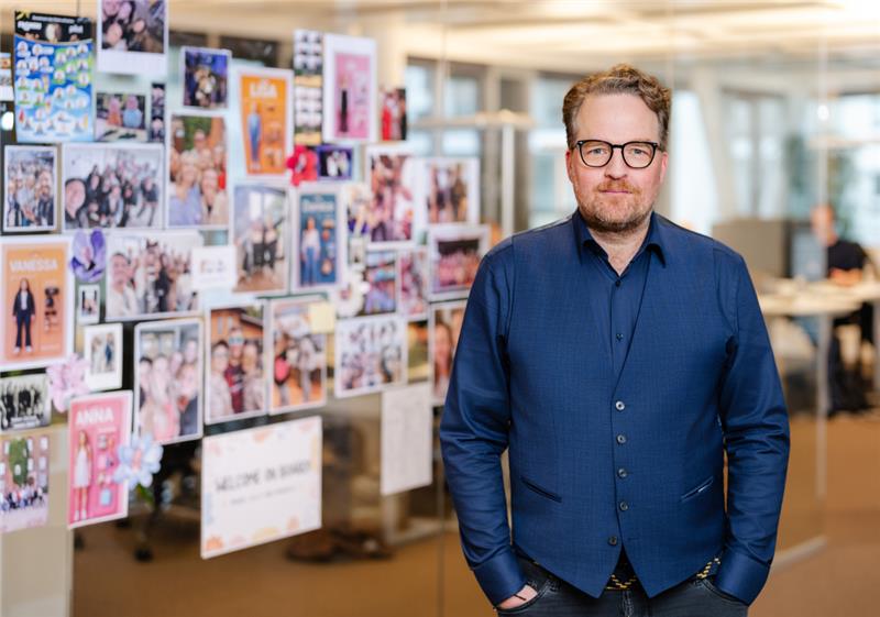 pilot Geschäftsführer Jörn Solfrian steht in einem blauen Hemd im Büro vor einer Glaswand mit bunten Zetteln.